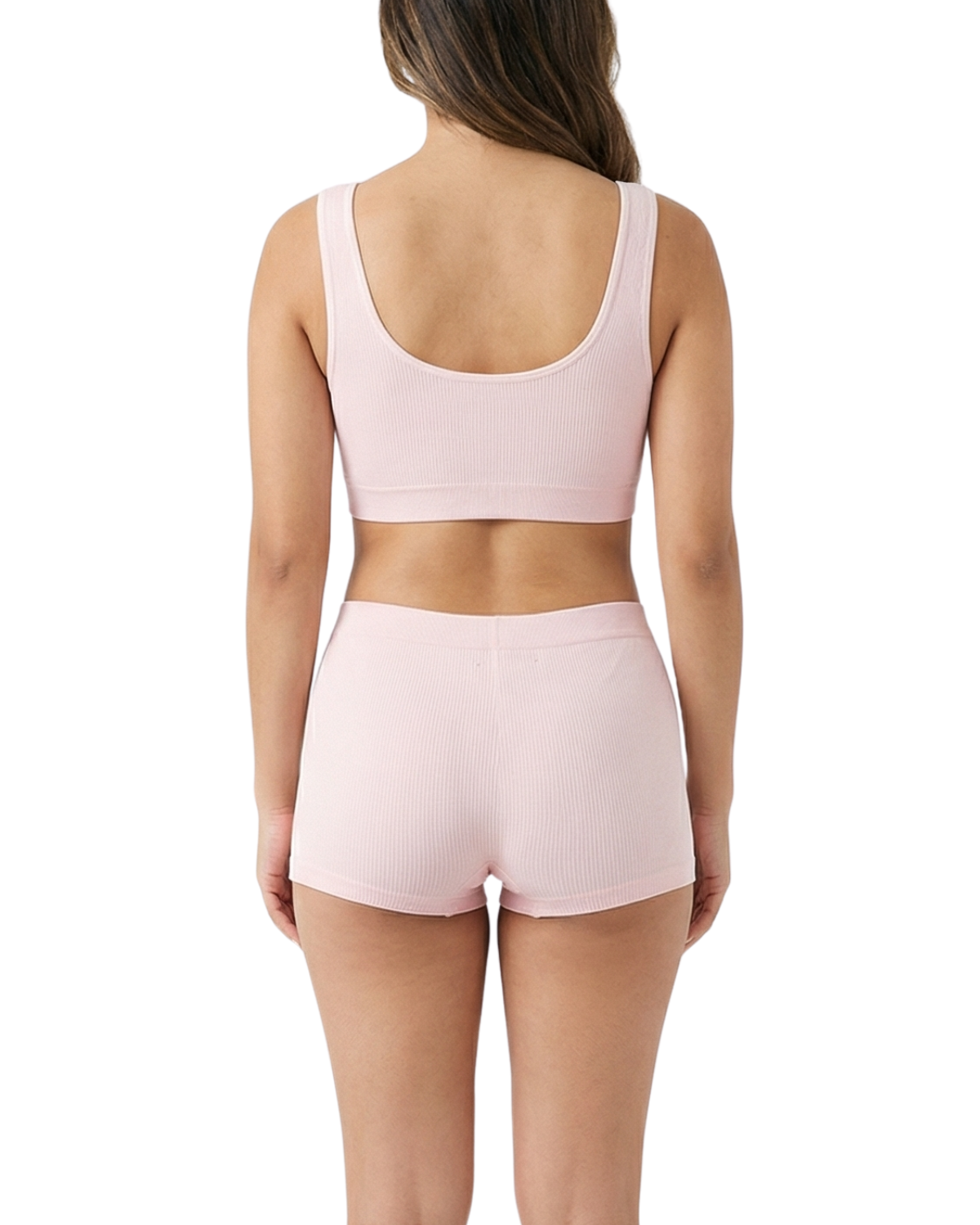 Woman wearing a pink sports bra and shorts set on a white background