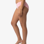 A woman modeling a light pink bikinis panty set against a plain light gray background.
