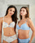 Two women wearing floral and blue bras with matching panties against a plain background