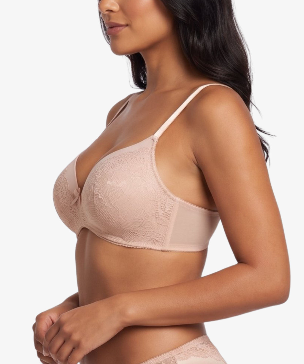 A woman modeling a light beige/nude lace bra and matching lace underwear against a plain light gray studio background.