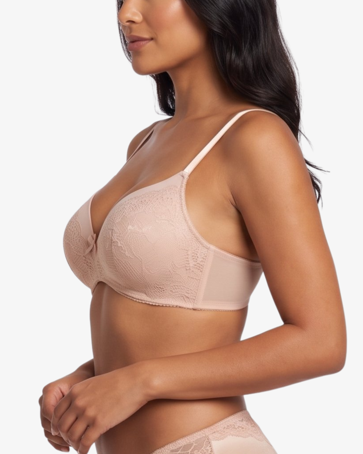 A woman modeling a light beige/nude lace bra and matching lace underwear against a plain light gray studio background.