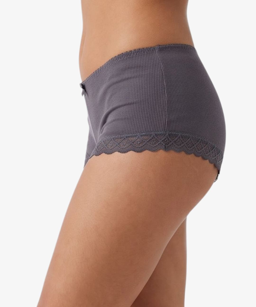 A close-up side view of a model wearing ribbed boyleg  grey underwear with a scalloped lace hem against a plain light background.