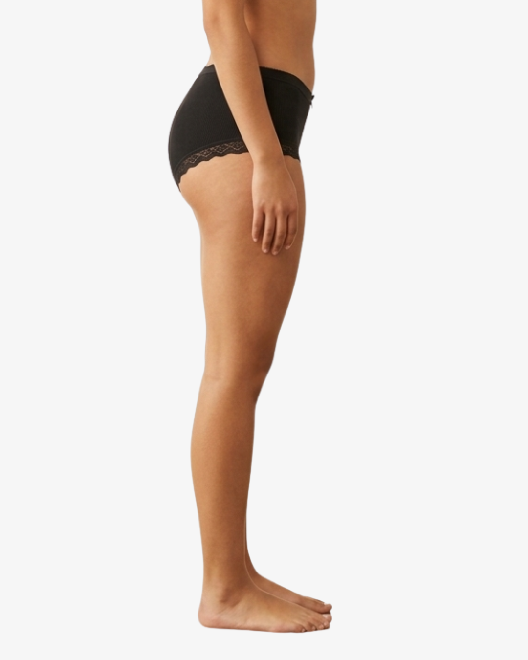 Side view of a model wearing black high-waisted briefs with a delicate lace trim at the hip, shown against a plain white background.