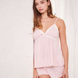 Woman wearing a light pink ribbed nightgown against a white background