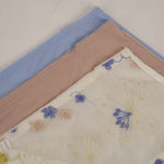 Three folded fabric samples with floral patterns on a light background
