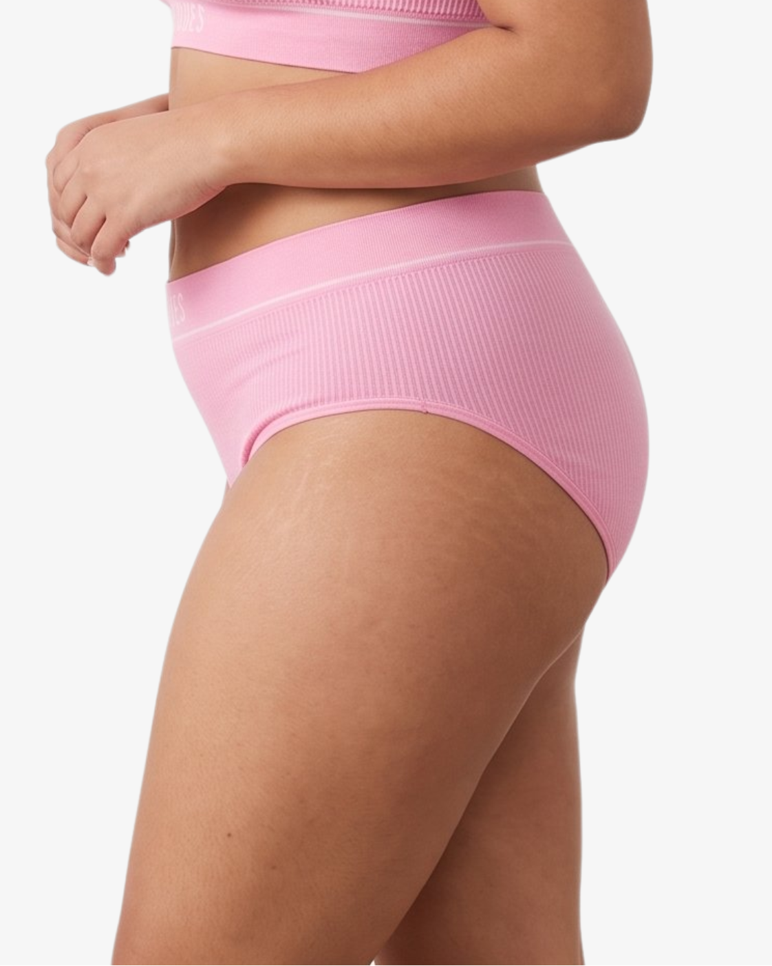 A woman modeling a ribbed high-waisted bikini against a light gray studio background.