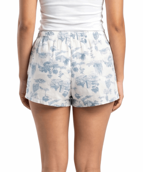 Woman wearing a white tank top and floral shorts on a white background