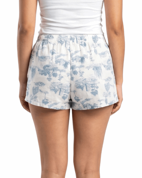 Woman wearing a white tank top and floral shorts on a white background