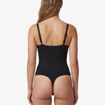 Rear view of a model wearing a black shapewear bodysuit with adjustable shoulder straps, set against a plain light gray background.