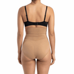 Woman wearing a black bra and mocha shapewear on a white background