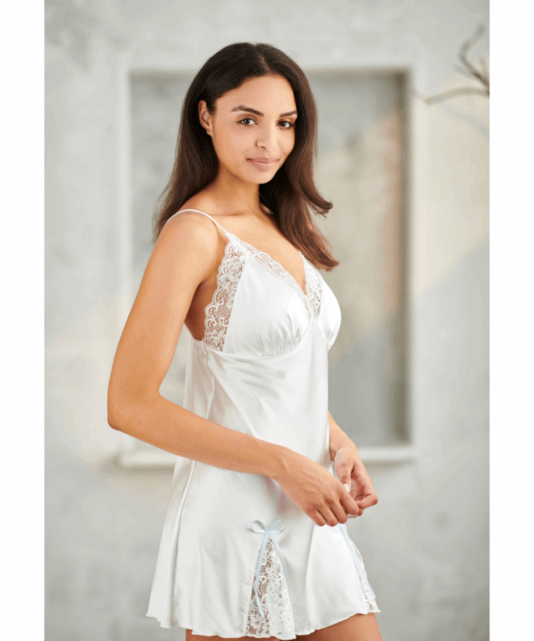 Woman wearing a white lace nightgown in a neutral setting