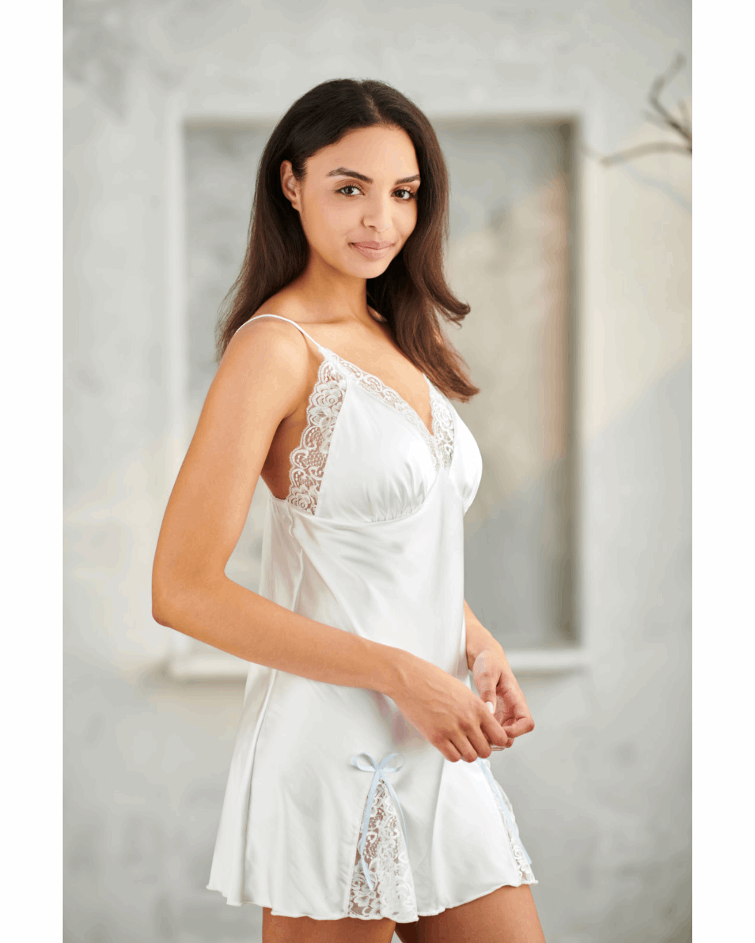 Woman wearing a white lace nightgown in a neutral setting