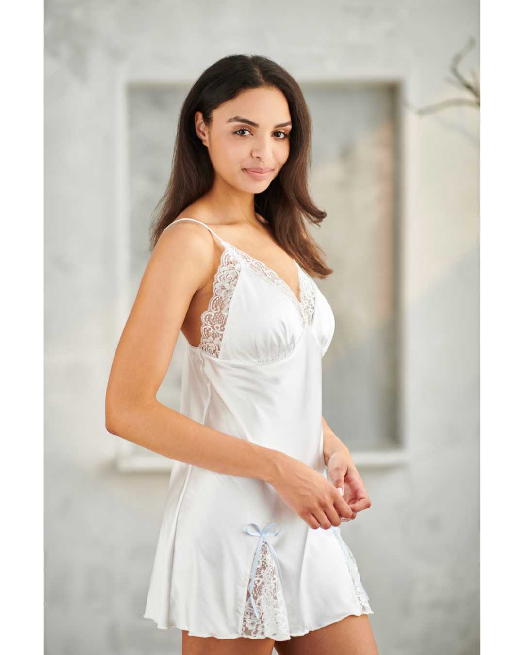 Woman wearing a white lace nightgown in a neutral setting
