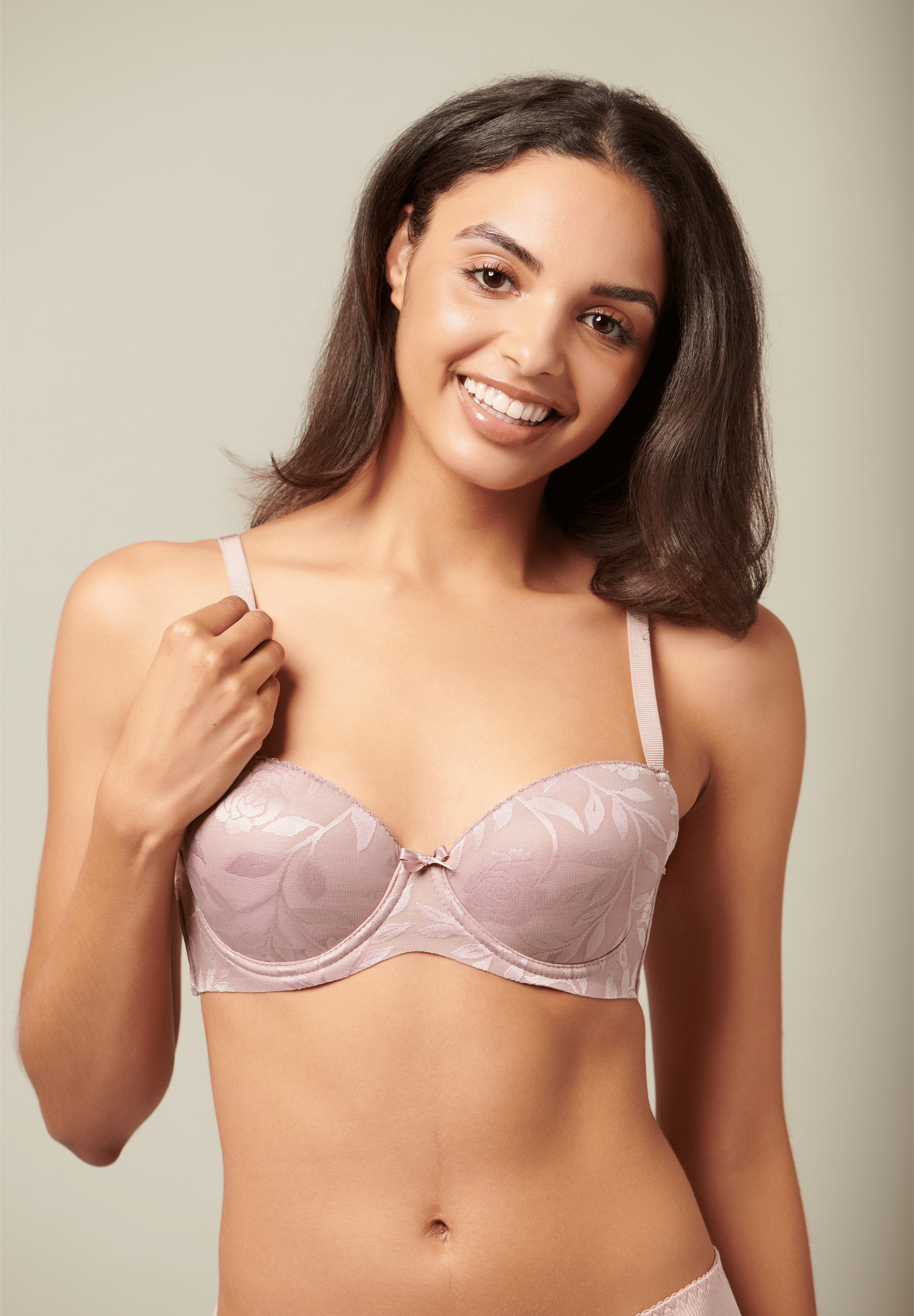 Woman wearing a light pink bra against a neutral background